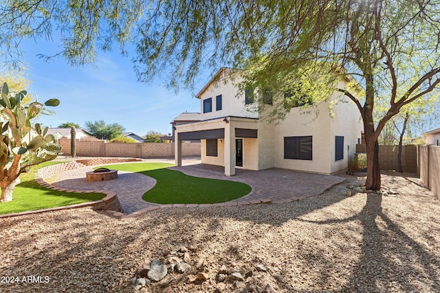 rear view of property featuring a patio area and an outdoor fire pit