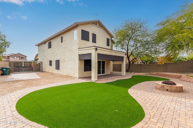 rear view of property featuring a patio area and a fire pit