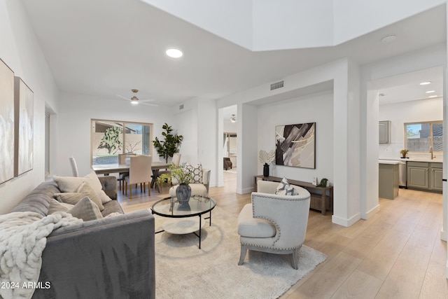 living room featuring ceiling fan, sink, and light hardwood / wood-style floors