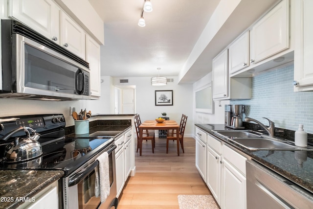 kitchen featuring white cabinets, stainless steel appliances, and hanging light fixtures