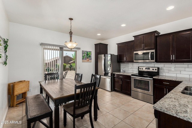 22403 W Harrison St, Buckeye, AZ 85326 - kitchen featuring stainless steel appliances, dark brown cabinetry, backsplash, light tile patterned floors, and light stone counters