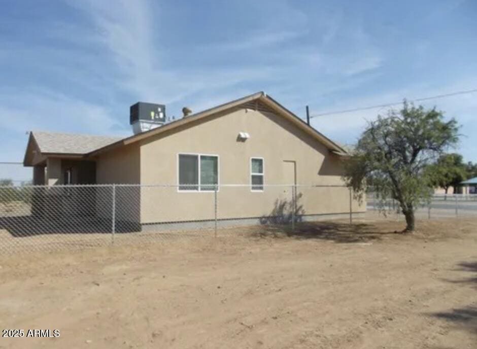 view of side of property with cooling unit, fence, and stucco siding