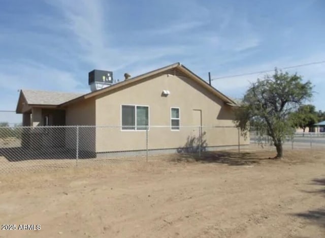 view of side of property with cooling unit, fence, and stucco siding