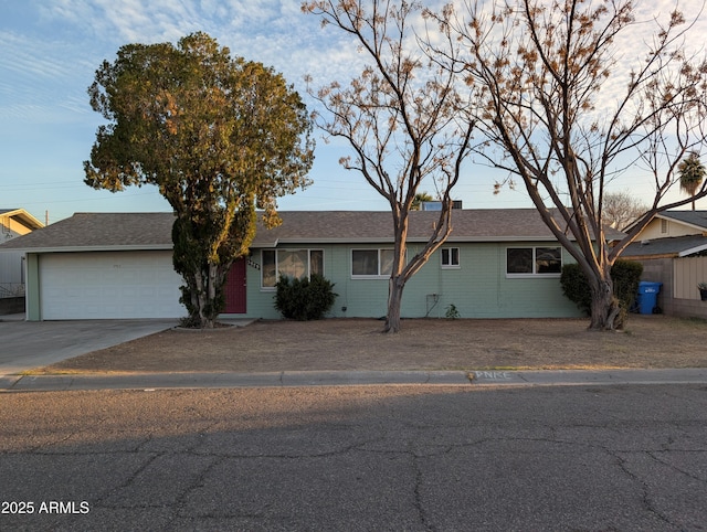 ranch-style home with a garage, brick siding, concrete driveway, and roof with shingles