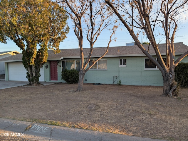 ranch-style house featuring a garage, driveway, and roof with shingles