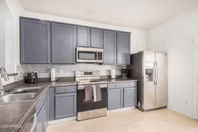 kitchen featuring stainless steel appliances, gray cabinets, tasteful backsplash, and sink