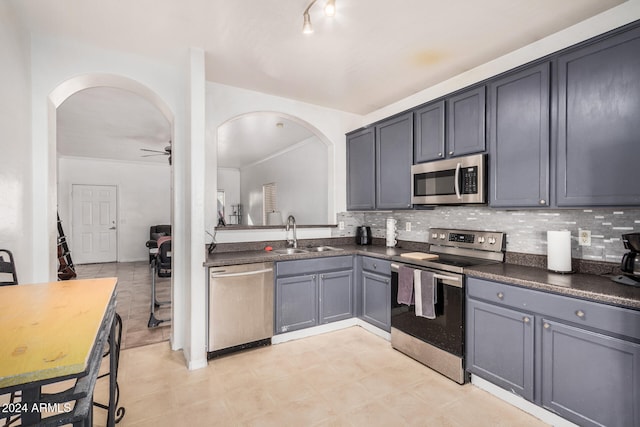 kitchen with backsplash, stainless steel appliances, ceiling fan, and sink