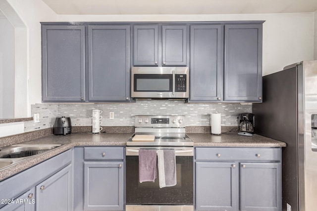 kitchen featuring decorative backsplash, gray cabinets, and appliances with stainless steel finishes