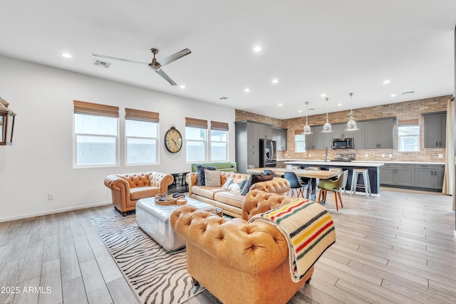 living room with ceiling fan, plenty of natural light, and light hardwood / wood-style flooring