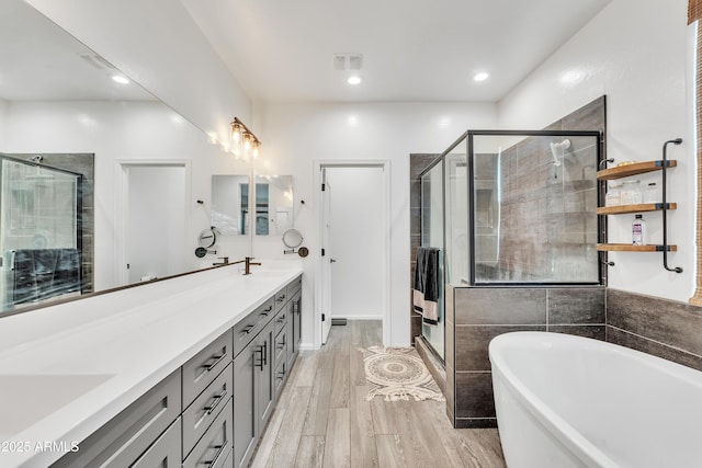 bathroom with hardwood / wood-style flooring, vanity, and separate shower and tub