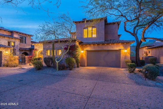 mediterranean / spanish house featuring a chimney, an attached garage, central AC unit, a gate, and driveway