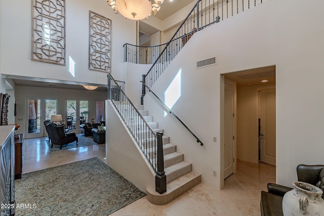 staircase featuring visible vents and a high ceiling