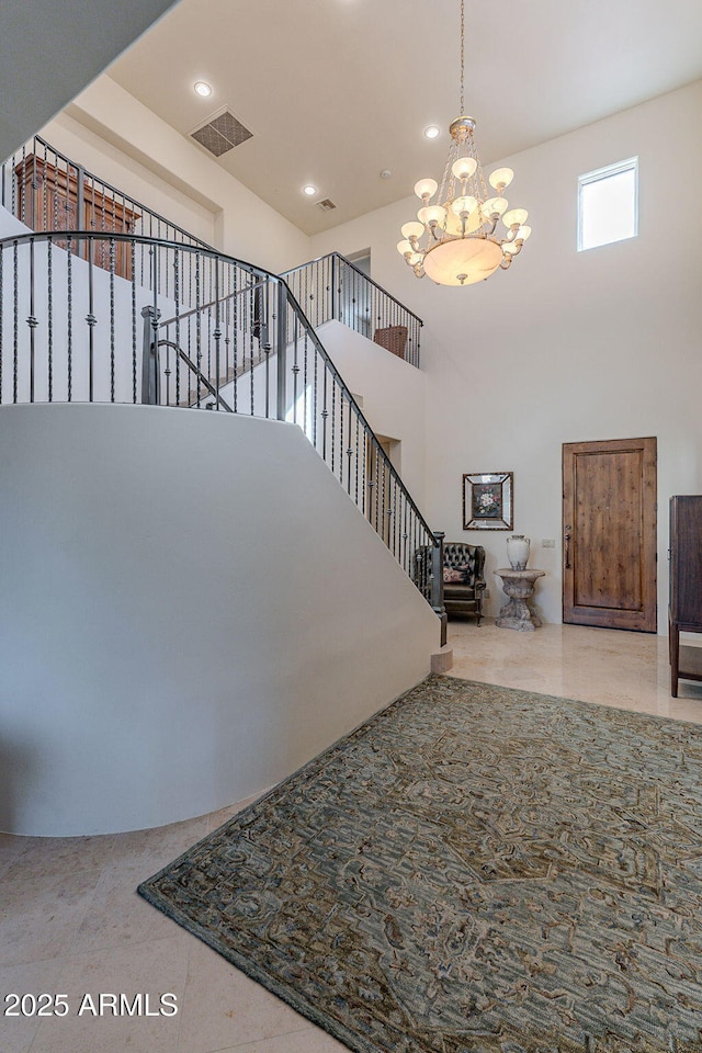 interior space with a towering ceiling, visible vents, stairway, and a chandelier