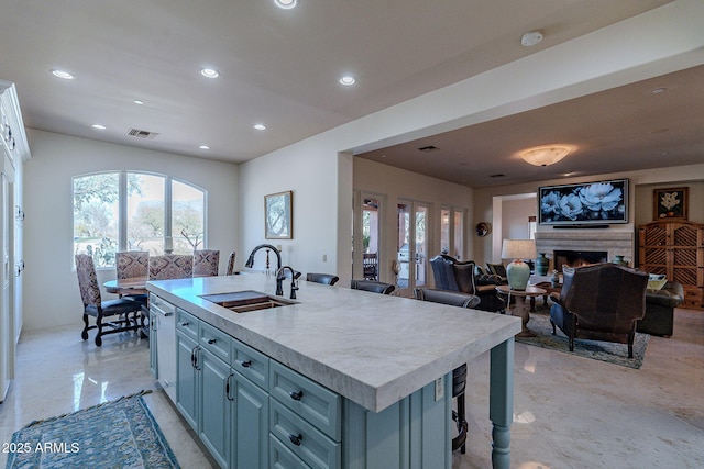 kitchen with recessed lighting, visible vents, a sink, and a lit fireplace