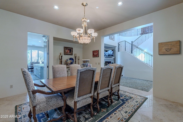 dining area featuring marble finish floor, a fireplace, recessed lighting, stairway, and a chandelier