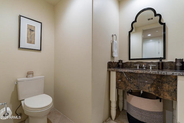 half bath featuring a sink, tile patterned flooring, and toilet