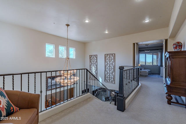 corridor featuring carpet floors, an inviting chandelier, recessed lighting, and an upstairs landing