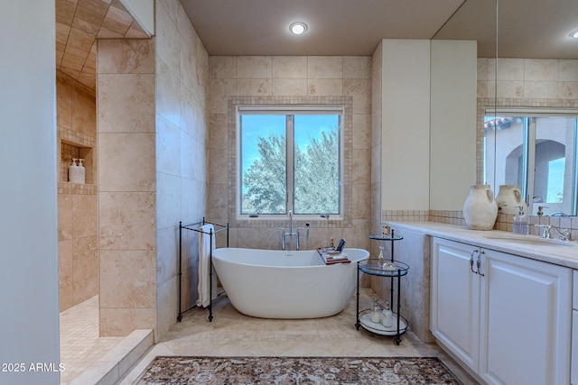 full bath featuring tile walls, vanity, tile patterned flooring, a freestanding tub, and tiled shower