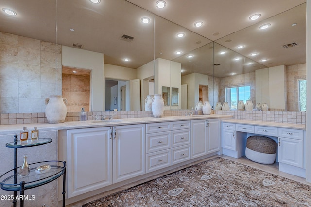 bathroom with a sink, visible vents, and decorative backsplash