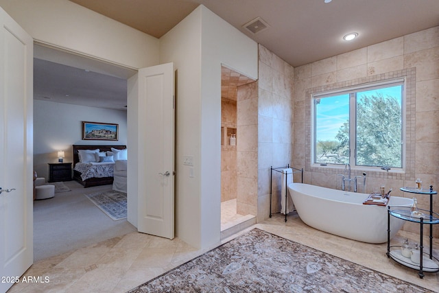 ensuite bathroom featuring ensuite bathroom, a freestanding tub, visible vents, tile walls, and walk in shower