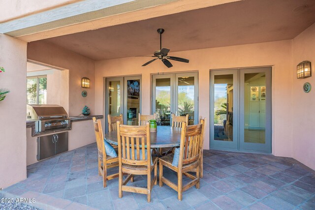 view of patio featuring outdoor dining area, a ceiling fan, french doors, exterior kitchen, and grilling area