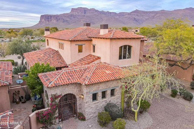 back of property featuring a chimney, a tile roof, a mountain view, and stucco siding