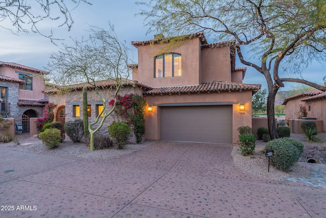 mediterranean / spanish-style home featuring a garage, concrete driveway, and stucco siding