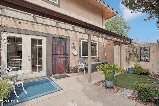 property entrance with french doors, a patio area, fence, and stucco siding