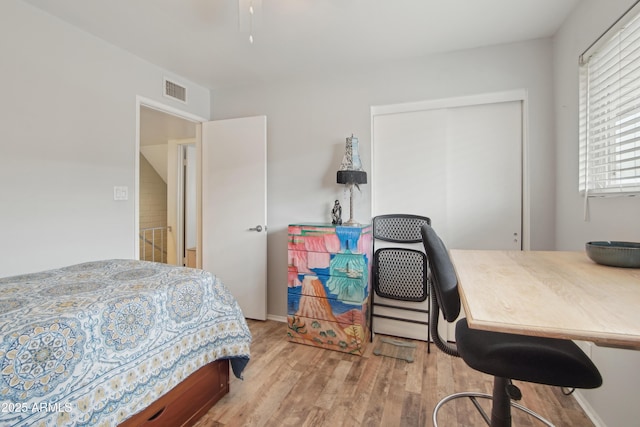 bedroom with a closet, wood finished floors, and visible vents