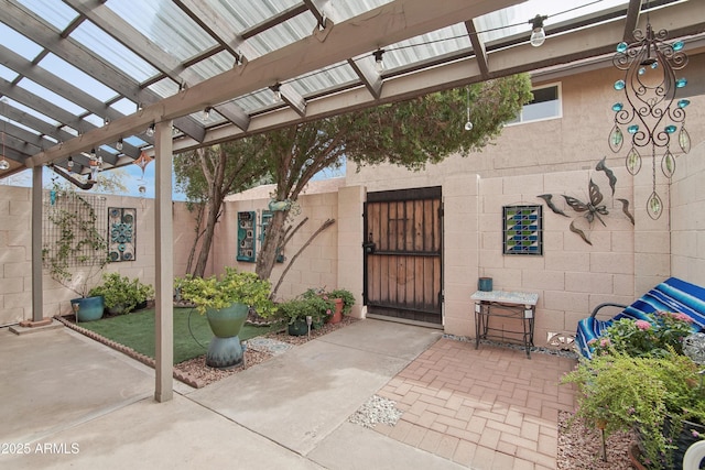 doorway to property featuring a gate, fence, concrete block siding, and a pergola