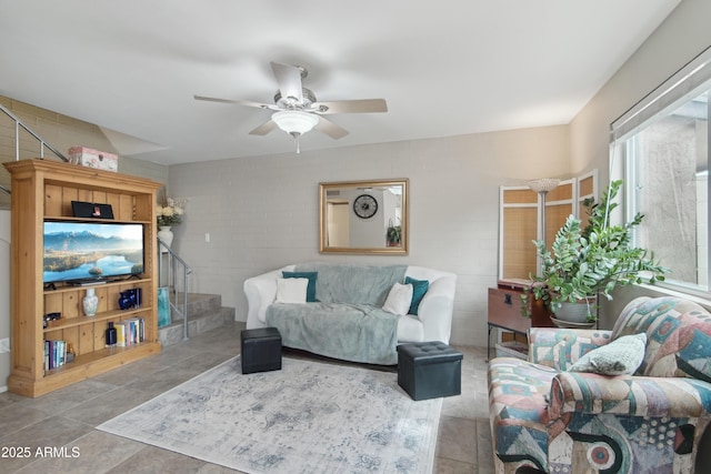 tiled living room with ceiling fan and stairway