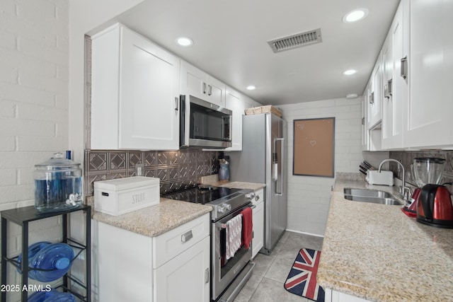 kitchen featuring a sink, visible vents, white cabinets, appliances with stainless steel finishes, and backsplash