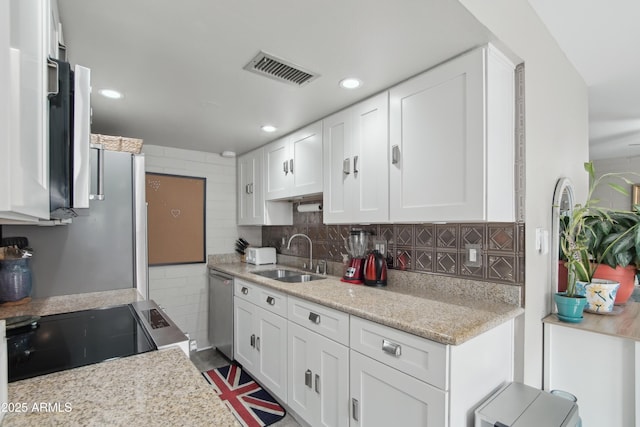 kitchen with stainless steel appliances, visible vents, decorative backsplash, white cabinetry, and a sink