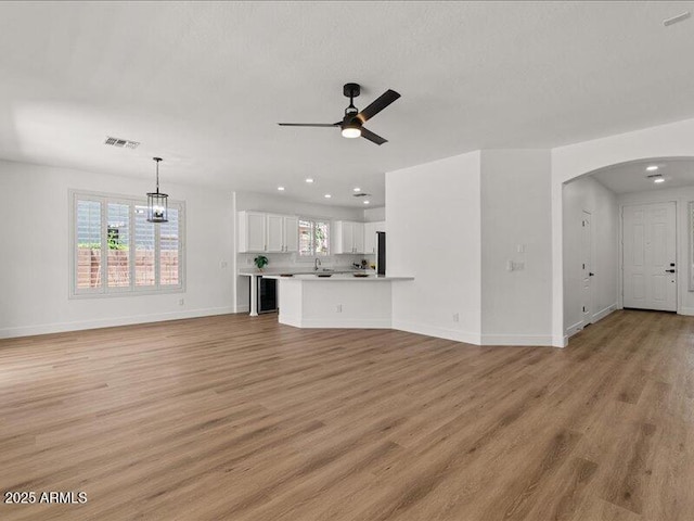 271 W Roadrunner Dr, Chandler, AZ 85286 - unfurnished living room featuring visible vents, baseboards, ceiling fan, arched walkways, and light wood finished floors