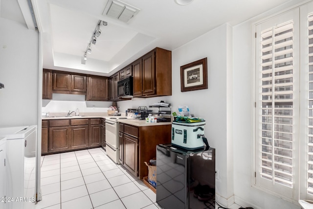 kitchen with track lighting, electric stove, sink, independent washer and dryer, and light tile patterned floors