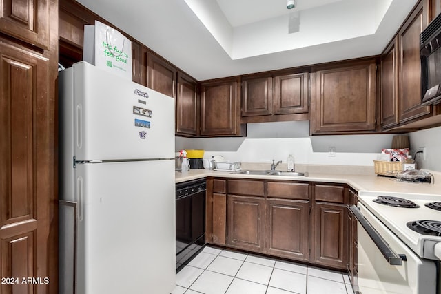 kitchen featuring dark brown cabinetry, a raised ceiling, sink, black appliances, and light tile patterned flooring