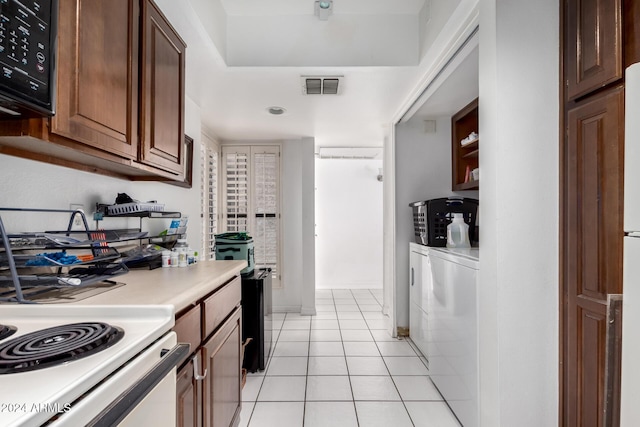 kitchen with white range oven, washing machine and clothes dryer, and light tile patterned floors