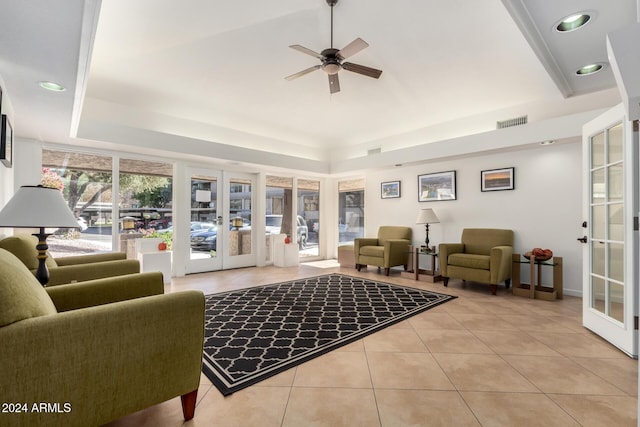 tiled living room featuring ceiling fan, french doors, and a tray ceiling