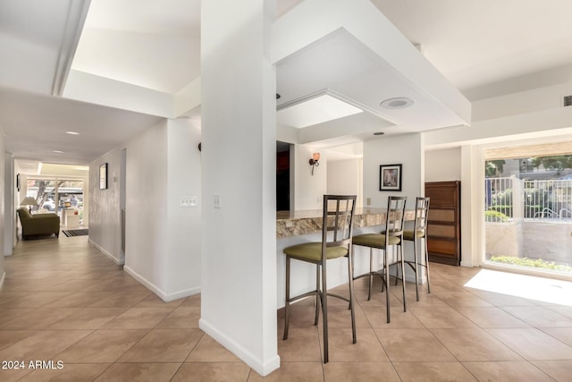 kitchen with a breakfast bar, a wealth of natural light, and light tile patterned flooring