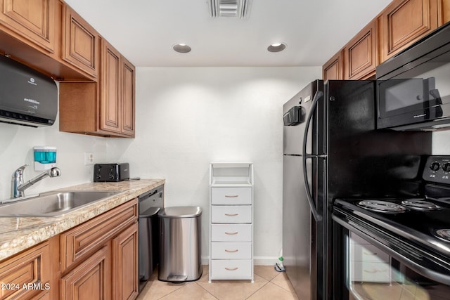 kitchen featuring light stone countertops, sink, light tile patterned floors, and black appliances