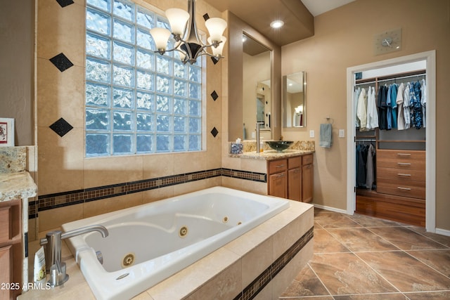 full bathroom featuring a walk in closet, a healthy amount of sunlight, vanity, and a tub with jets