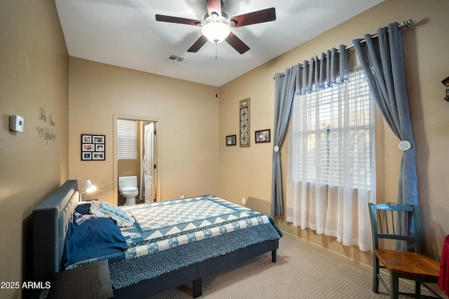 bedroom with ensuite bath, visible vents, and a ceiling fan