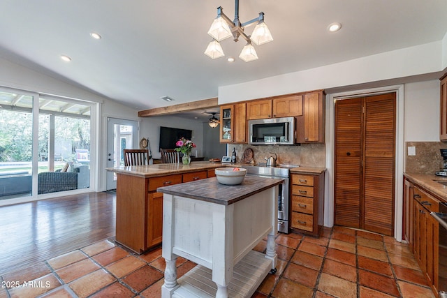 kitchen featuring appliances with stainless steel finishes, wood counters, brown cabinetry, tasteful backsplash, and vaulted ceiling