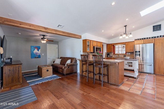 kitchen with a kitchen breakfast bar, visible vents, brown cabinets, a peninsula, and stainless steel appliances