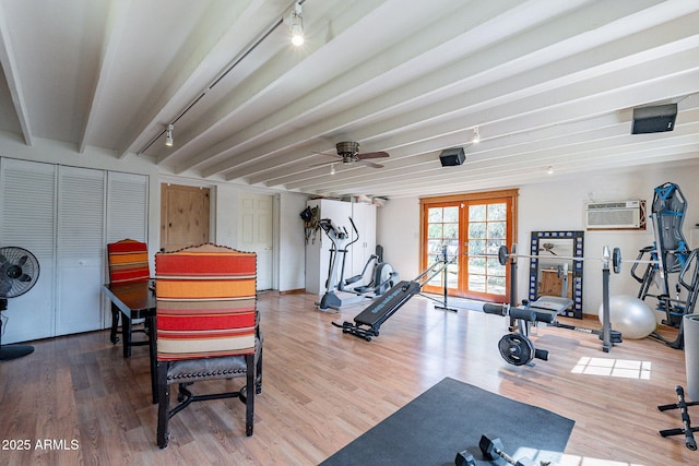 workout room featuring a ceiling fan, an AC wall unit, and wood finished floors