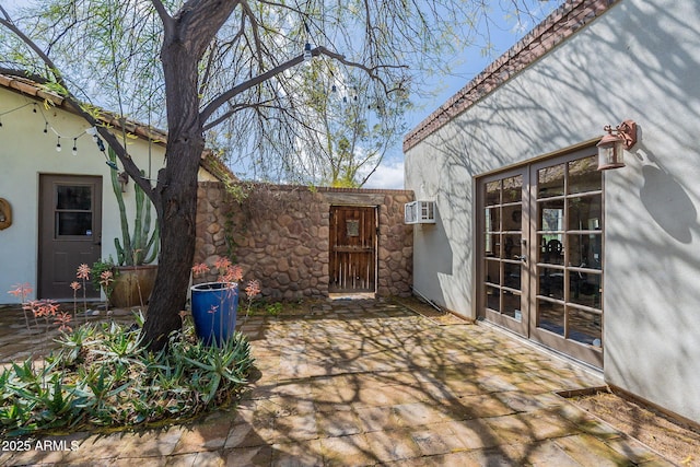 view of patio / terrace featuring fence, french doors, and a wall mounted air conditioner