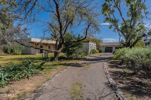 view of front of house with a garage, stucco siding, and gravel driveway