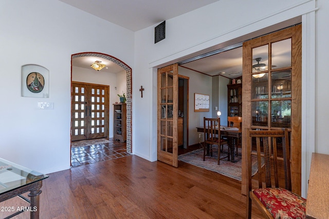 foyer entrance featuring visible vents, baseboards, wood finished floors, and french doors