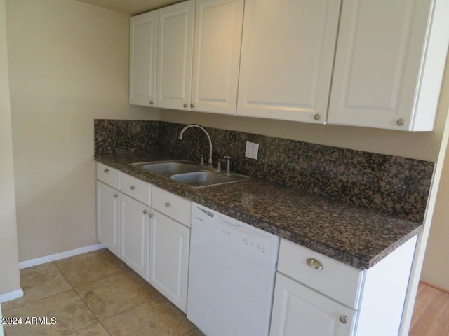 kitchen featuring dark stone counters, white dishwasher, sink, light tile patterned floors, and white cabinetry