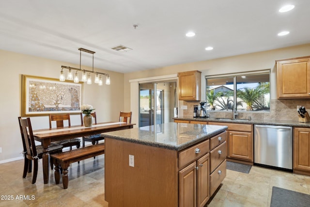 kitchen with sink, decorative light fixtures, dishwasher, a kitchen island, and a wealth of natural light